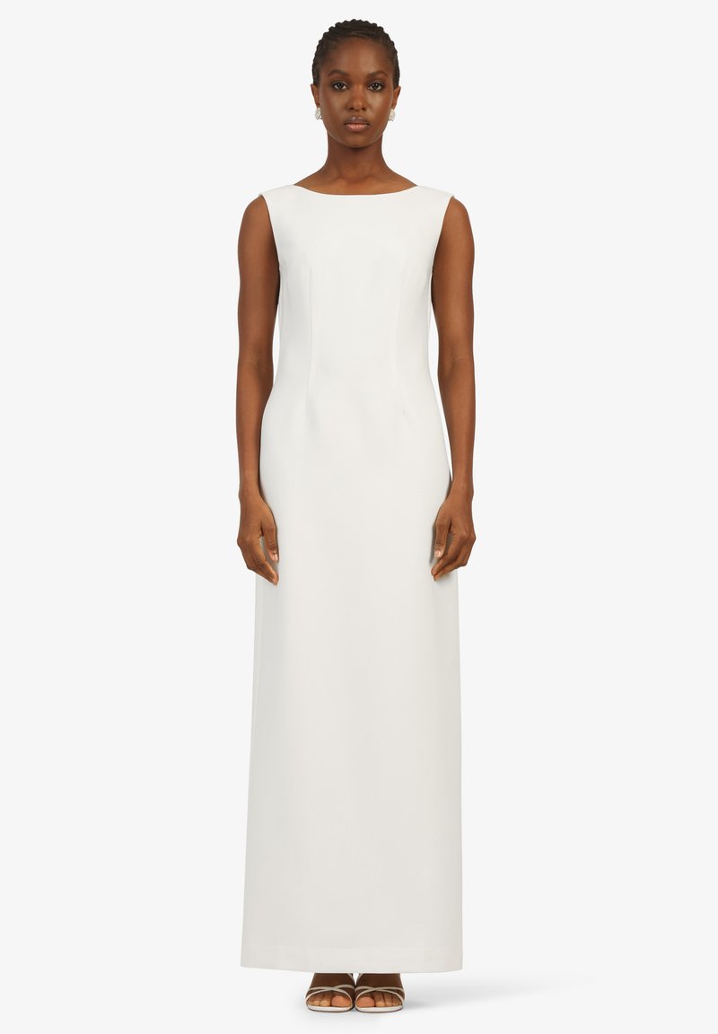 Robe blanche longue sans manches avec une coupe ajustée, décolleté carré et tissu lisse. Le tissu tombe droit jusqu'au sol.