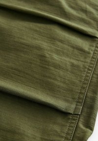 Olive green fabric with a smooth texture, featuring folded layers and visible stitching along the edges. No distinct patterns or hardware.