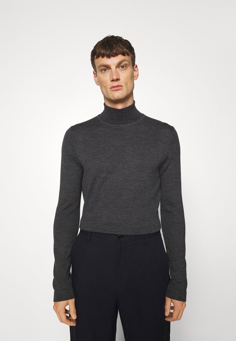 Pull à col roulé gris foncé en maille fine, manches longues, design ajusté, associé à un pantalon sombre. Style minimaliste, sans motifs.