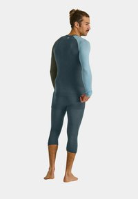 Long-sleeve athletic shirt and cropped leggings in gradient blue and dark gray, made of stretchy material with minimal seams and a fitted design.