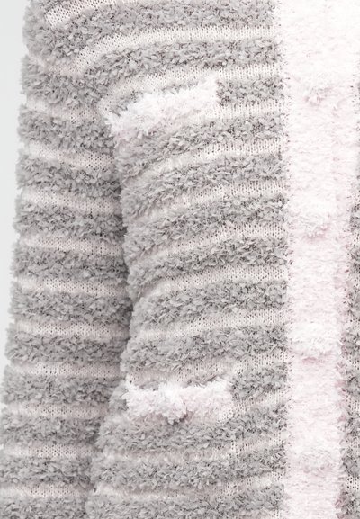 Μαλακό, αφράτο πλεκτό ύφασμα με υφή σε οριζόντιες ρίγες ανοιχτού γκρι και απαλού ροζ, με κοντινή λήψη μανικιού και λεπτομέρειας στο μπροστινό μέρος.