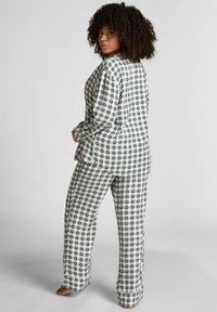 Sprawdzony zestaw piżamowy w kremowym i ciemnozielonym kolorze. Koszula z długim rękawem ma kołnierzyk i guziki; spodnie mają luźny krój i elastyczny pas.