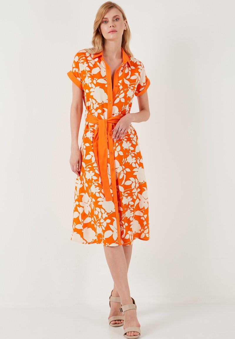 Blumenhemdkleid in leuchtendem Orange mit weißen Blumenmustern. Kurze Ärmel, durchgehende Knopfleiste und passender Stoffgürtel. Glatte Textur.