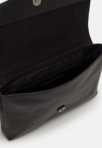 Pochette en cuir noir avec une surface texturée, dotée d'une fermeture à bouton-pression et d'un intérieur spacieux en tissu noir.