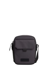 Bolso bandolera de nylon gris con cierre de solapa, correa ajustable y un parche de logo texturizado en la parte frontal. Forma rectangular compacta.