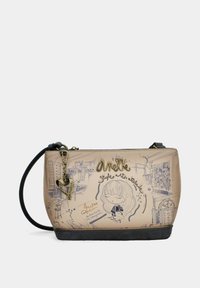 Bolso de mano sintético beige con base negra, que presenta diseños de boceto y acentos dorados, incluyendo un charm en forma de corazón y el logo de la marca.