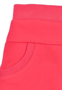 Roze joggingsbroek met een brede elastische tailleband, zijzak, een gladde textuur, en geribbelde details bij de taille en zak.