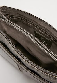 Šedá kožená kabelka otevřená, aby ukázala dva hlavní oddíly a vnitřní kapsu na zip s textilním podšíváním.