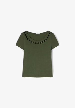 Oliwkowa koszula z krótkim rękawem i dekoltem w kształcie litery U, ozdobiona rzędem czarnych oczek wokół kołnierza.