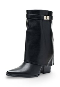 Bottine en faux cuir noir avec un bout pointu et un talon bloc. Présente un revers replié et un accent de boucle métallique. Texture lisse.