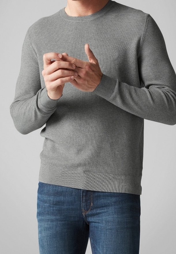 Suéter gris de punto con cuello redondo, puños y dobladillo acanalados. Combinado con jeans de mezclilla azules, destacando los detalles de la textura en la tela.