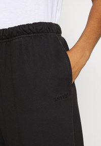 Svarta sweats med elastisk midja, sidofickor och en strukturerad yta. Har en diskret Levi's-logotyp i matchande svart.
