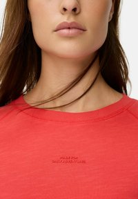 Rode sweatshirt met ronde hals, met reliëftekst "MADE FOR DAILY ADVENTURES." Eenvormige structuur, casual ontwerp, minimalistische stijl.