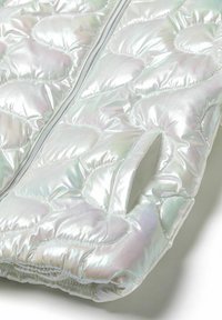 Iridescent uppblåsbar jacka med quiltat mönster, med dragkedja och sidofickor, tillverkad av glansigt, mjukt tyg.
