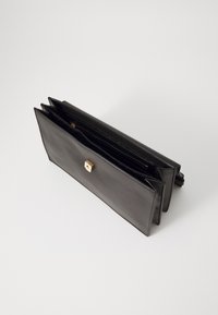 Punguță din piele neagră cu o textură netedă, dotată cu un închizător hardware patrata aurie și multiple compartimente interioare pentru organizare.