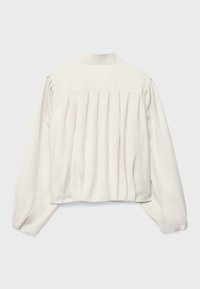 Blouse blanche à manches longues avec des plis froncés dans le dos, des manches légèrement bouffantes et un petit col droit.