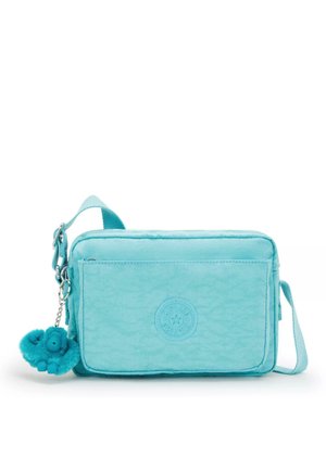 Turquoise fabric crossbody bag, rectangular shape, featuring a textured surface, front logo detail, and a furry keychain accessory.