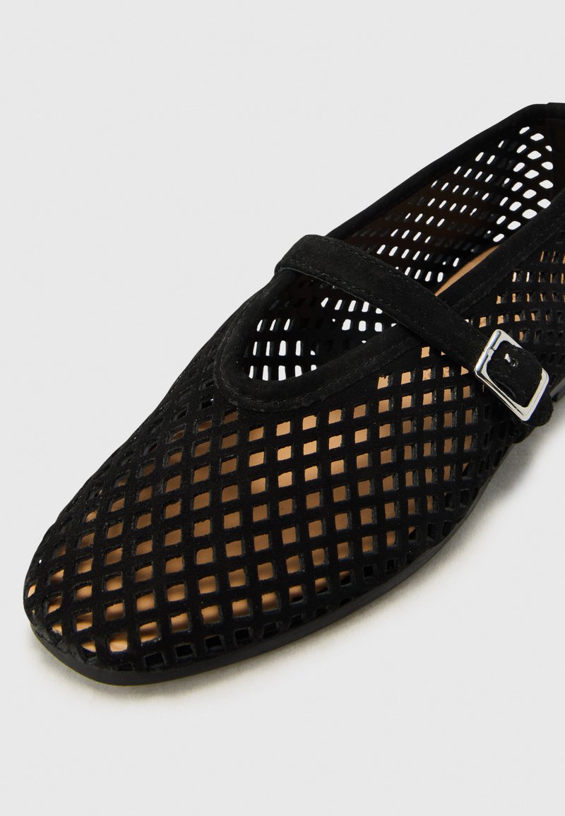 Czarne siateczkowe buty z zaokrąglonym czubkiem, z gładkim paskiem na podbiciu i małą srebrną klamrą. Teksturowana powierzchnia z wzorem wycięć.