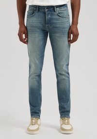 Blugi din denim de culoare albastru deschis, cu o croială ajustată, ușor uzată și design cu cinci buzunare. Asortați cu adidași bej și albi, cu talpă joasă.