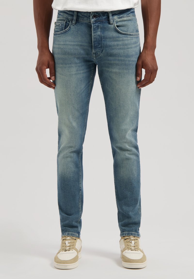 Blugi din denim de culoare albastru deschis, cu o croială ajustată, ușor uzată și design cu cinci buzunare. Asortați cu adidași bej și albi, cu talpă joasă.