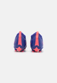 Des chaussures de football violettes avec des accents roses, présentant une tige texturée, un onglet au talon et des crampons en forme d'étoile sur la semelle pour la traction.