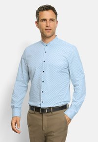 Hellblaues Langarmhemd mit Stehkragen, das ein gepunktetes Muster in dunklerem Blau aufweist, mit schwarzen Knöpfen verschlossen.