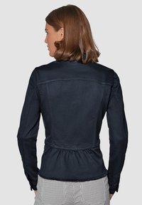 Donkerdenim jasje met een peplum taille, op maat gemaakte naden en lange mouwen, met ruwe zoomdetails en een klassieke kraag.