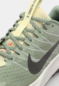 Bežecká obuv Nike Wildhorse 10 má svetlozelený a žltý sieťový vrch, textúrované šedé akcenty a výrazné čierne logo swoosh.