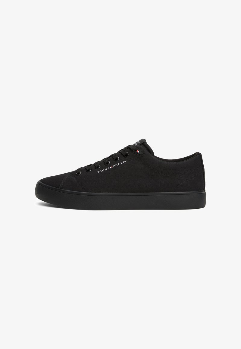 Baskets en toile noires avec un bout rond, semelle plate noire et six oeillets. Présente la marque "TOMMY HILFIGER" en blanc sur le côté.