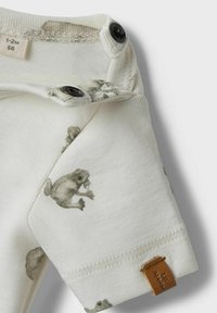 Tutina bianca in cotone con stampe di animali grigie. Presenta chiusure a scatto sulla spalla e una piccola etichetta di stoffa marrone sull'orlo.