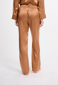 Satin, braune Lounge-Hose mit elastischem Bund. Sie hat eine lockere Passform und gerade Beine und weist eine glatte, glänzende Textur auf.