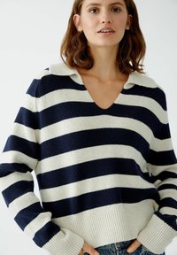 Marineblau und creme gestreifter Pullover mit V-Ausschnitt und Kragen. Weicher Strick und gerippte Bündchen und Saum. Lässige Passform mit lockeren Ärmeln.