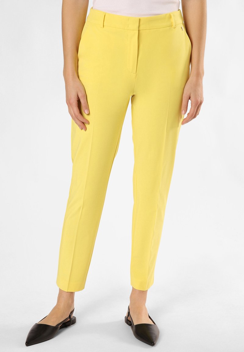 Pantalon jaune ajusté avec une coupe slim, doté d'un devant plat et de poches latérales. Tissu lisse avec un léger éclat et chevilles effilées.