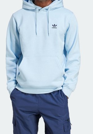 Hoodie Adidas bleu clair avec une poche kangourou à l'avant, associé à un pantalon cargo bleu marine, visible du cou jusqu'au milieu des cuisses.
