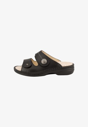 Zwarte open-toe slide-sandaal met twee verstelbare riemen, metalen knoopdetail, zacht beige voetbed en lage sleehak.