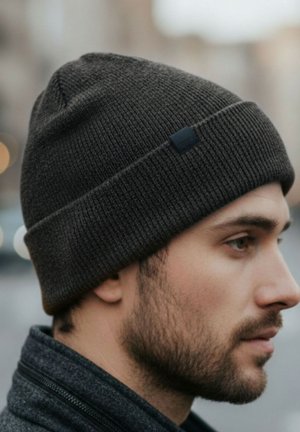 Dark gray knit beanie with a folded cuff, textured pattern, and a small black logo tag on the side, worn on a person’s head.