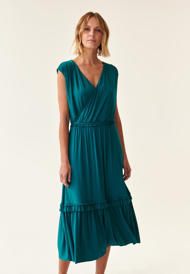 Robe portefeuille en teal en tissu léger, avec des manches courtes, une taille cintrée et un ourlet volanté pour une touche supplémentaire.