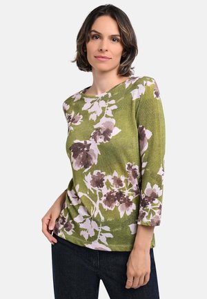 Grünes Blumenoberteil mit rundem Halsausschnitt, 3/4-Ärmeln und Mustern aus weißen und lila Blumen. Weicher Stoff mit leichtem Glanz.