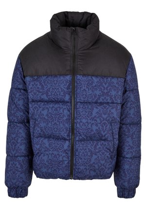 Párnázott dzseki fekete felső résszel és sötétkék, bonyolult mintázattal az alján. Magas gallérral és elülső cipzáras záródással rendelkezik.