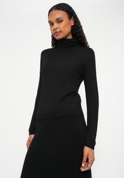 Pull noir à col roulé avec des manches longues, en tissu tricoté doux. Design ajusté avec une texture lisse et de subtils accents côtes à l'ourlet.