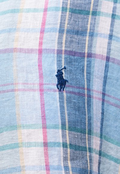 Tela ligera con patrón de cuadros multicolores y pequeño logo bordado de jugador de polo en azul marino en el centro.