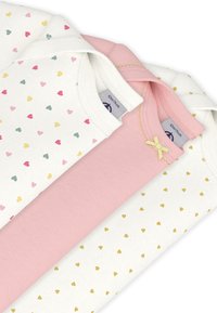 Τρία βρεφικά μπλουζάκια: ένα λευκό με πολύχρωμες καρδιές, ένα μονόχρωμο ροζ και ένα λευκό με χρυσές καρδιές. Μαλακό βαμβακερό ύφασμα με στρογγυλές λαιμόκοψεις.