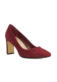 Red suede high-heeled shoe, pointed toe, and a chunky beige heel. Smooth interior with seamless stitching, minimalistic design.