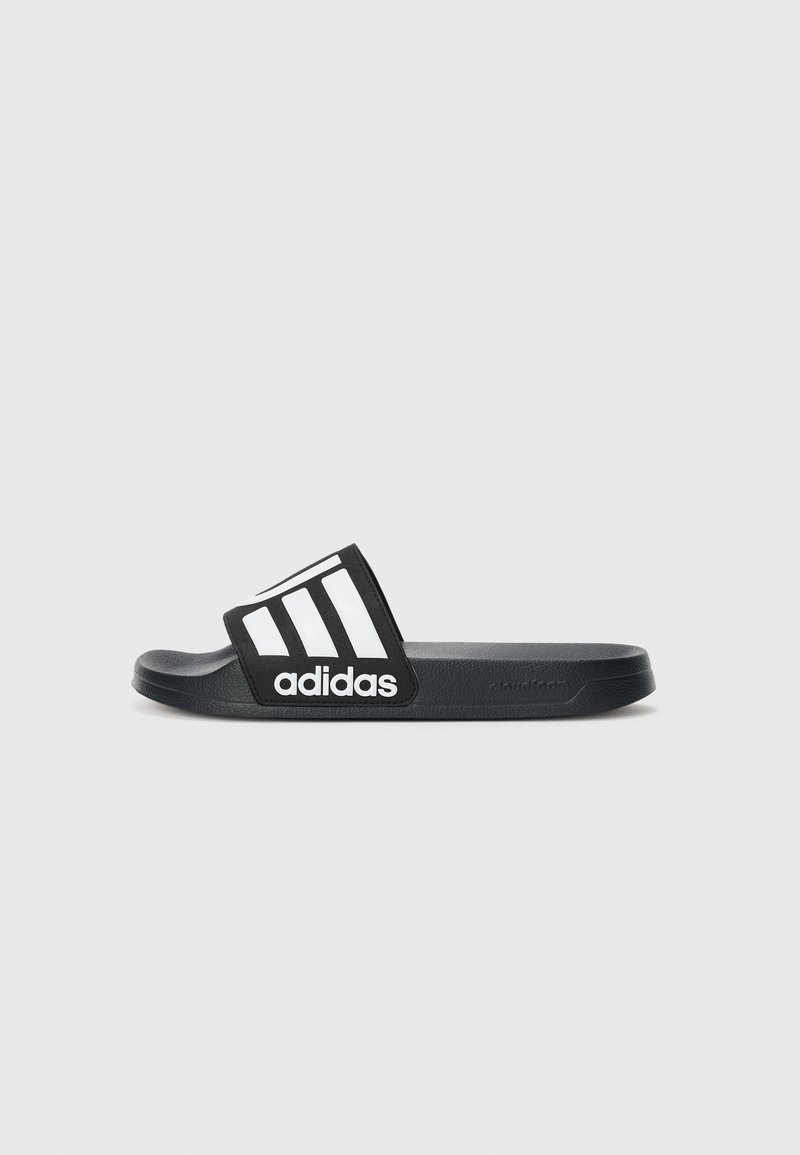 Sort Adidas slide sandal med hvidt tre-stripes logo over remmen, flad sål og tekstureret fodseng på en ensfarvet lys baggrund.