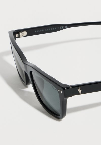 Μαύρα ορθογώνια γυαλιά ηλίου με σκοτεινούς φακούς, ασημένιο λογότυπο Polo στο πλαϊνό μέρος και σήμανση Ralph Lauren στο εσωτερικό του βραχίονα.