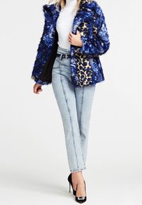 Blå og sort kunstpelsfrakke med leopardprint detaljer, parret med højtaljede lyse denimjeans og sorte stiletter.