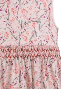 Blumenkleid aus hellrosa Stoff mit einem ganzflächigen Druck von kleinen orangefarbenen und lila Blumen, ausgestattet mit einem gerafften, smockierten Taillenbund.