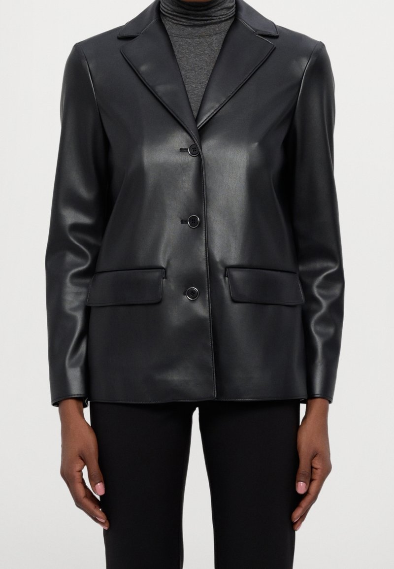 Svart konstläderblazer med kammade slag, enfaldig knappstängning och två framfickor. Slät textur med minimal sömnad.