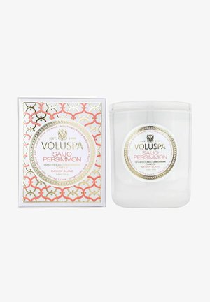 Voluspa Saijo Persimmon stearinlys i et klart glasbeholder, pakket i en hvid æske med et rosa og guld geometrisk mønster. Bemærkelsesværdigt logo på beholderen.