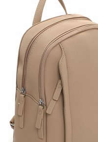 Beež seljakott kahe välise lukuga taskuga, sile materjal, peen õmblus ja ülemise käepidemega. Kompaktne ristkülikukujuline.